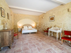 Full view of the Passeron room: exposed stone walls, King-size bed, and traditional tiles